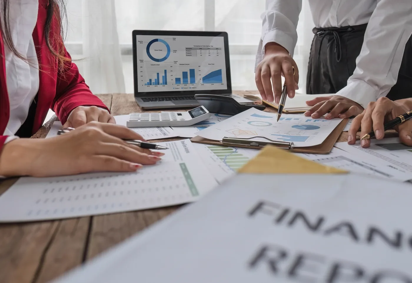Fizibilite çalışması: dizüstü bilgisayardaki projeksiyon grafikleri, hesap makinesi ve üzerinde “Financial Report” yazan basılı rapor.